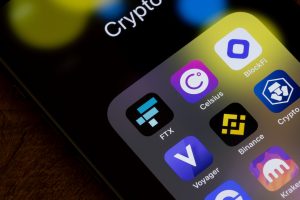 Close-up of a smartphone screen showing cryptocurrency app icons including FTX, Celsius, Binance, Voyager, BlockFi, and Kraken, symbolizing the collapse of major crypto platforms.
